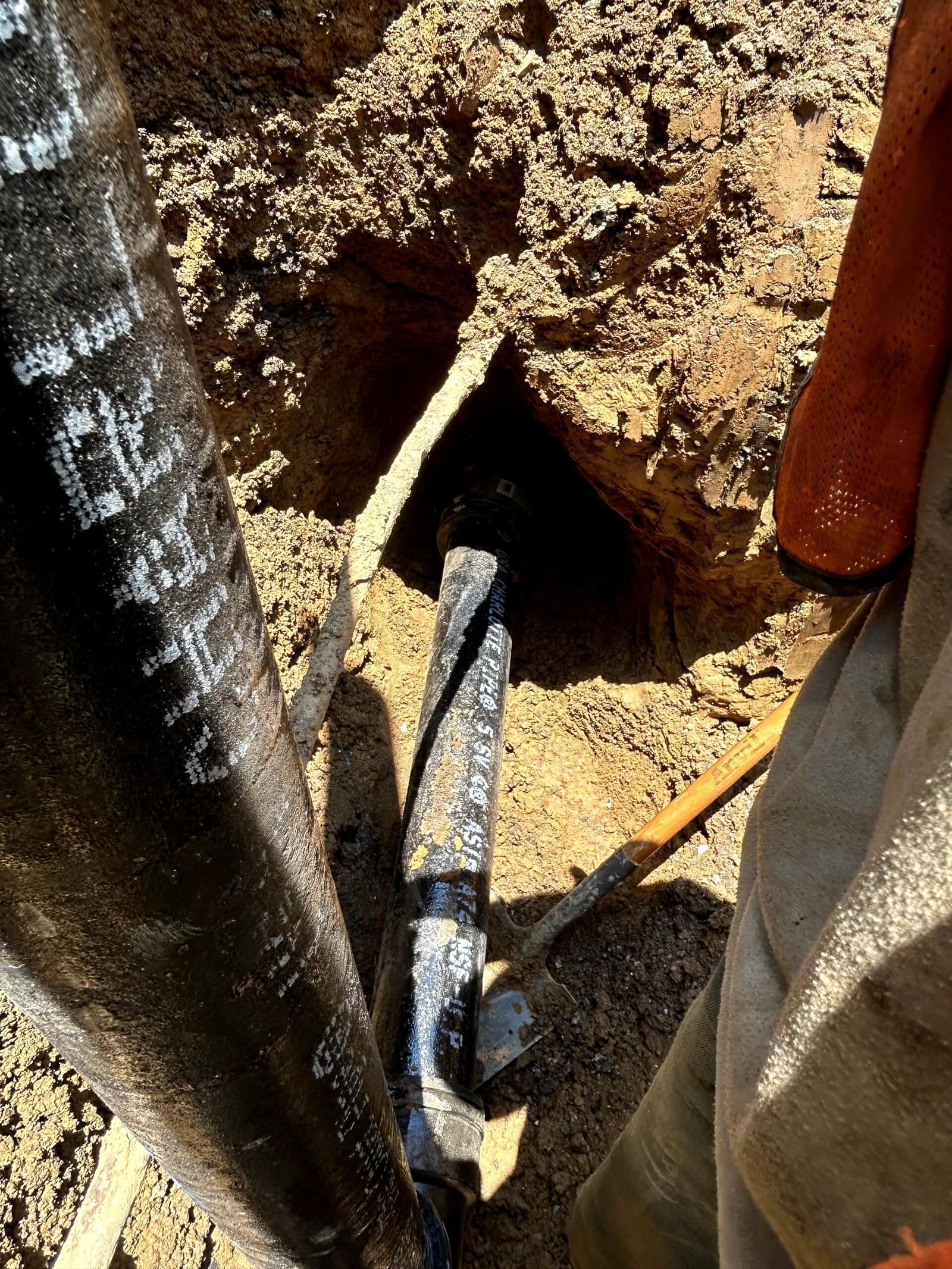 A water service line exposed in a hand-dug trench